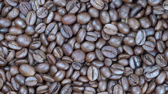 Fried coffee beans background, close up, rotation loopable 4k top view. Food  background. Gastronomy concept, organic food. Macro coffee beans