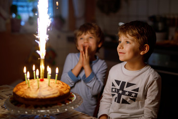 Two beautiful kids, little preschool boys celebrating birthday and blowing candles