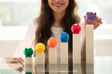 Businesswoman Placing Piggybank On Growing Graph