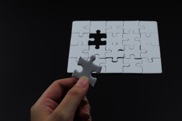 Hand put the jigsaw piece of puzzle to complete 