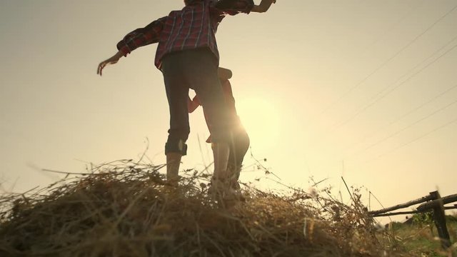 Two boys jumping on a haystack slow motion
