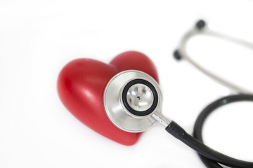 Stethoscope around a red rubber heart on a white background; concept of health healthy heart or cardio examination.