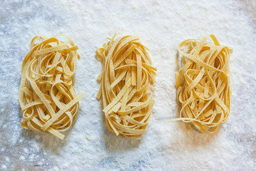 Fresh homemade pasta with pasta ingredients on the dark wooden table top view.