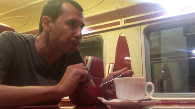 man at night eating soup in the train restaurant railway lifestyle cat drinks coffee. man on the train concept journey travel railway