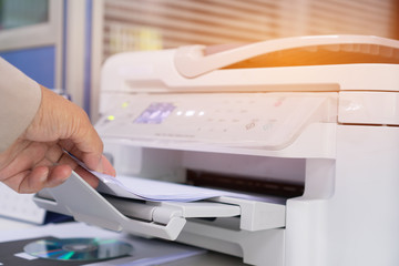 Business Documents concept : Businesswoman hands working in process press of paper in laser printer on busy work desk office. Soft focus