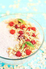 Smoothie bowl with oats, raspberry and peanut butter on blue wooden background. Healthy summer breakfast.