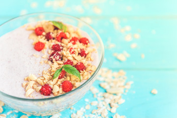 Smoothie bowl with oats, raspberry and peanut butter on blue wooden background. Healthy summer breakfast.