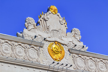 Obraz premium Gilded coat of arms of Soviet Union closeup on facade of pavilion Space on VDNH in Moscow on a sunny summer morning