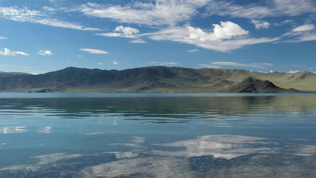 Waters of mongolian lake Tolbo-Nuur surrounded by mountains in north Mongolia under sky and clouds