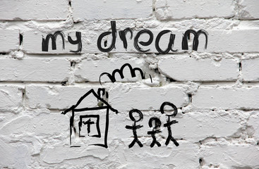 Brick wall with children's drawing of the house and family