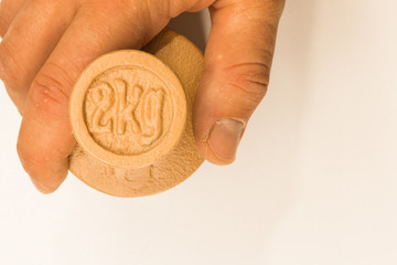 Fototapeta premium Hand holds 2kg weight balance measurement on white background