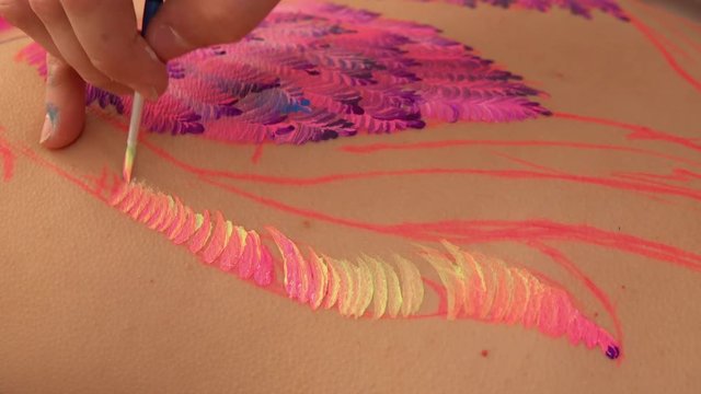 Talented painter works in petrykivka style drawing. Juicy colors on the skin.