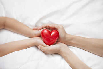 Fototapeta premium Mother's Day celebration with woman holds young kid's hands supporting red heart gift, and charity donation for nursing children concept.