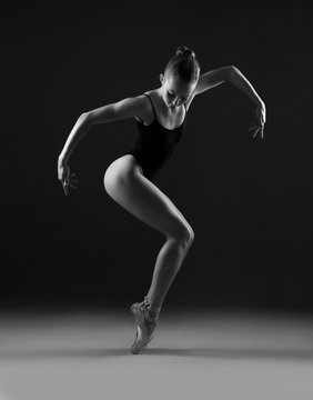 Ballerina in black leotard in a geometric pose. Black and white photo.