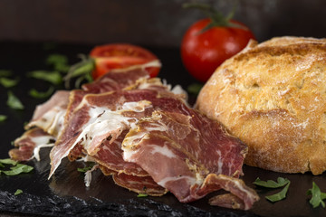 Slices of smoked prosciutto near a bread bun
