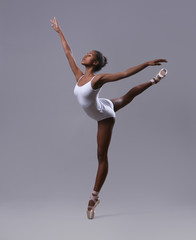 A ballerina in a white leotard makes a pose "Swallow"