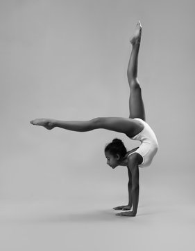 Flexible girl in white leotard. Black and white photo.
