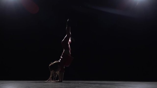 Little child does a handstand in the studio. Black background. Slow motion