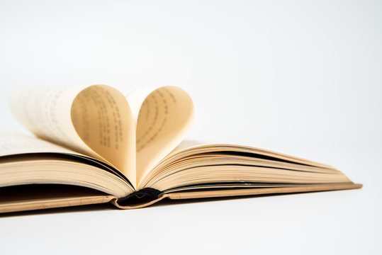 close up of opened book with heart shaped from two pages, isolated on white background.