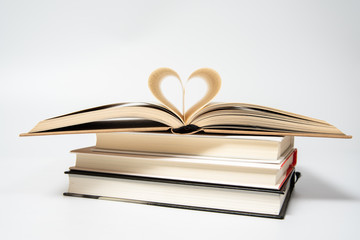 close up of opened book with heart shaped from two pages, isolated on white background.