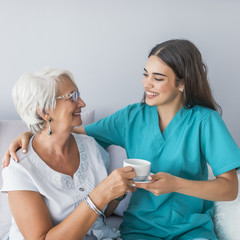 Happy senior woman talking with friendly nurse at geriatric ward