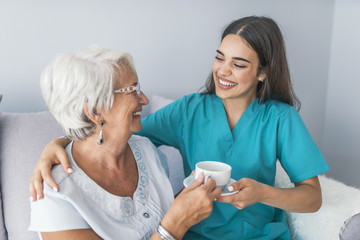 Happy senior woman talking with friendly nurse at geriatric ward