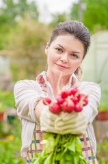 smiling woman with a bunch of radish in the garden