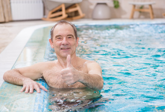 Senior man in the pool showing thumbs up. Space for text