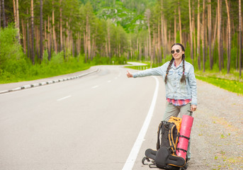 Fototapeta na wymiar young woman hitchhiking along a road