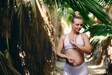 Pregnant woman in sportswear in tropical nature