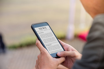 News article concept on phone screen. Man holding smartphone reading news article on screen. - 219416862