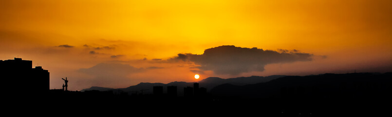Fototapeta premium At sunset, the sky turns orange and the city becomes a silhouette