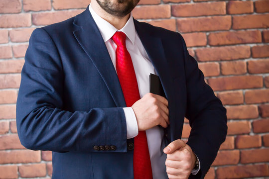 Businessman In A Red Tie Hides A Purse In His Jacket Pocket