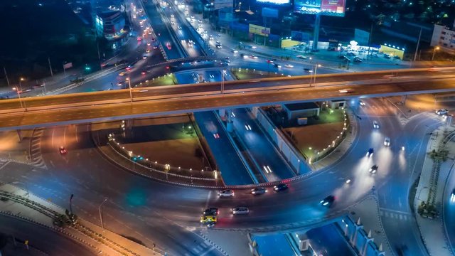 Hyperlapse timelapse moving go right circular of night city traffic on 4-way stop street intersection circle roundabout in bangkok, 4K UHD horizontal aerial view.