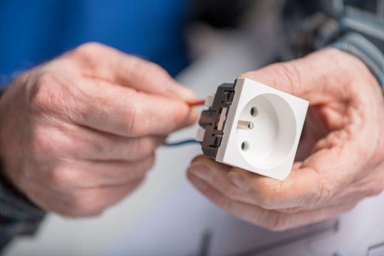 Electrician connecting a wire into a power socket