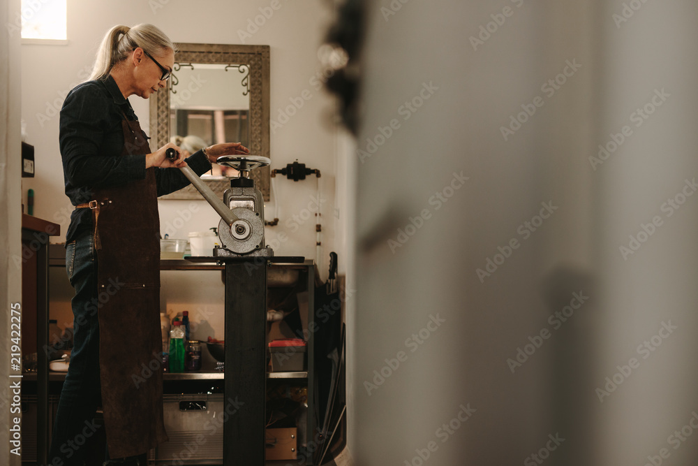 Wall mural Mature woman working in goldsmith workshop