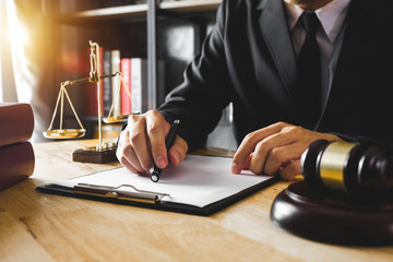 Justice and law concept.Male judge in a courtroom with the gavel,working with,digital tablet computer docking keyboard, eyeglasses,on wood table 