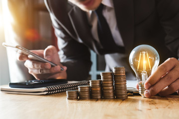 accountant working on desk in office using calculator and smartphone to calculate budget. concept finance and accounting in morning light