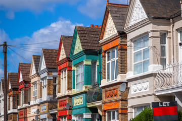 A row of colourful terraced houses in London with with a LET sign