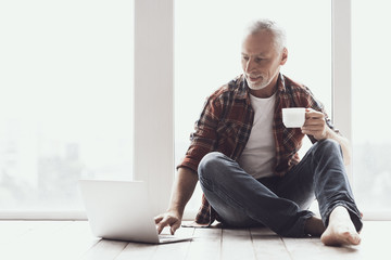 Smiling Mature Man with Beard Using Laptop at Home