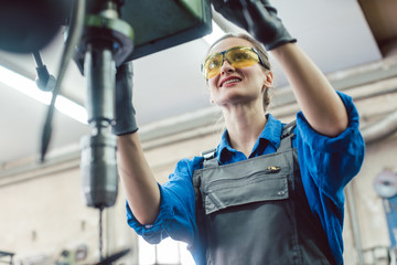 Arbeiterin in Schlosserei arbeitet an der Bohrmaschine