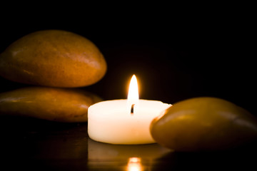 Obraz na płótnie Canvas Bright stones and candle on a dark background