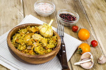 Rice with chicken meat and garlic in wooden bowl