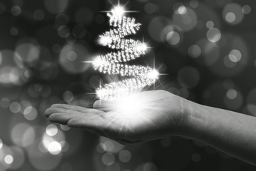 Bright Christmas lights in female hand, creating a Christmas tree on black background