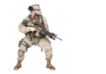 Studio shoot of modern infantry soldier, U.S. marine rifleman in combat uniform, helmet and body armor, screaming and crouching down with assault service rifle in hands isolated on white background