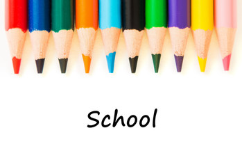 Color pencils in row isolated on white background.Text school.