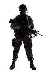 Full length, low key studio shoot of fully equipped army soldier in camo uniform and helmet, armed...