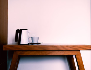 Hot coffee in ceramic Coffee Cup and Kettle on the wooden table and white wall background