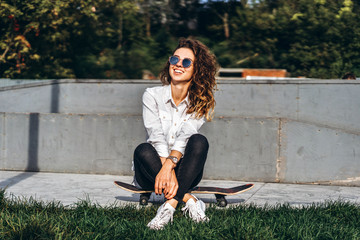 Cute girl with curly hair with skateboard in the park