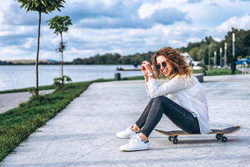 Cute girl with curly hair with skateboard in the park